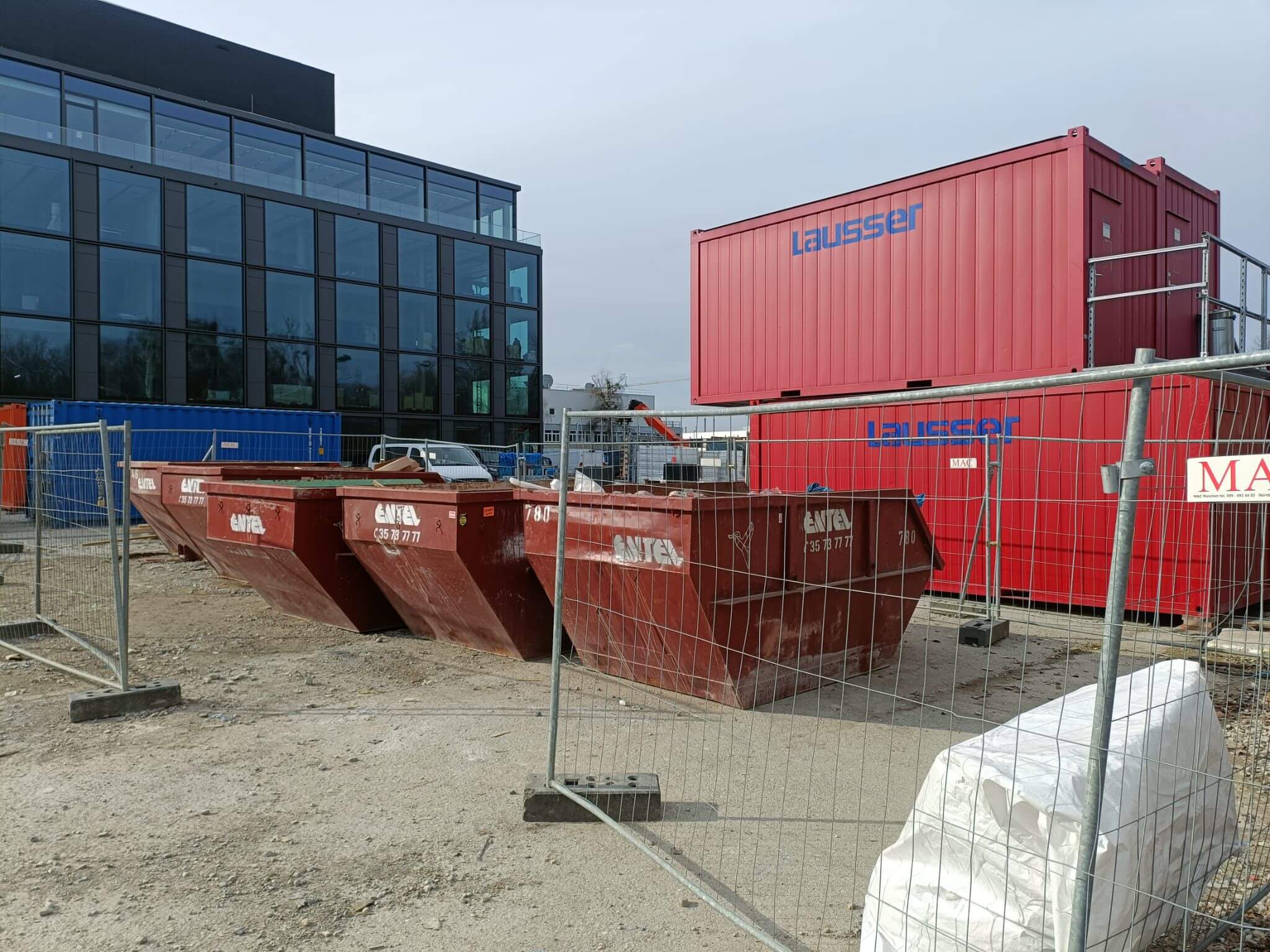 Drei Entel-Absetzcontainer auf einer Baustelle vor einem Bürogebäude-Neubau