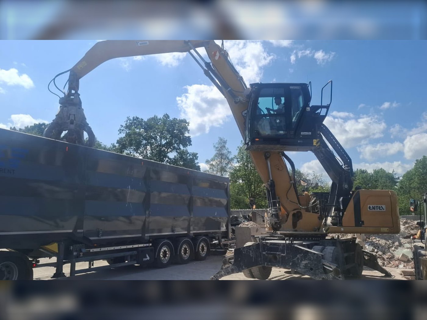 Fünf rot-braune Entel-Absetzcontainer mit Firmenlogo, gestapelt auf dem Schrottplatz