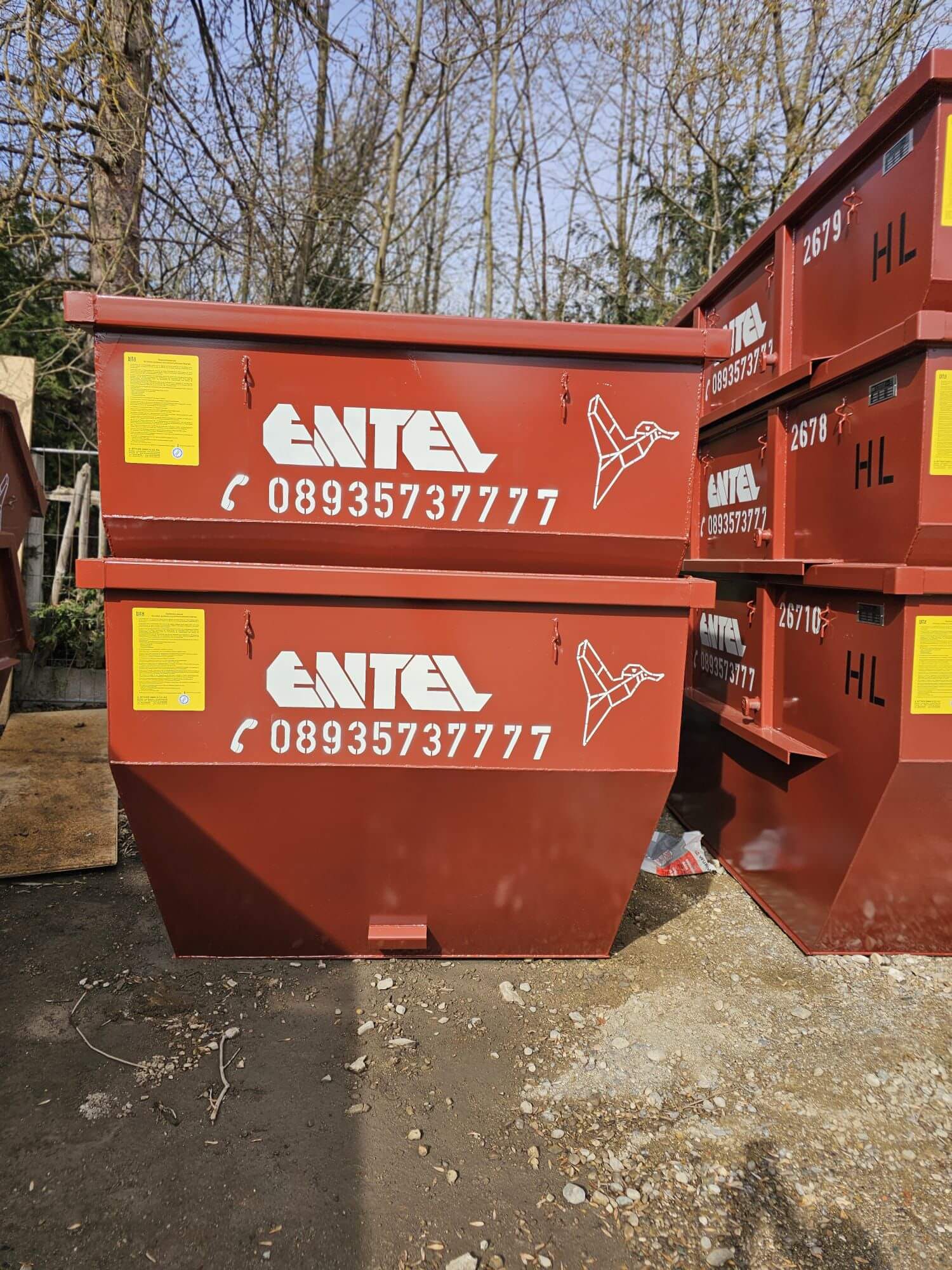 Zwei rot-braune Entel-Absetzcontainer mit Firmenlogo, im Hintergrund weitere nummerierte Container auf dem Schrottplatz