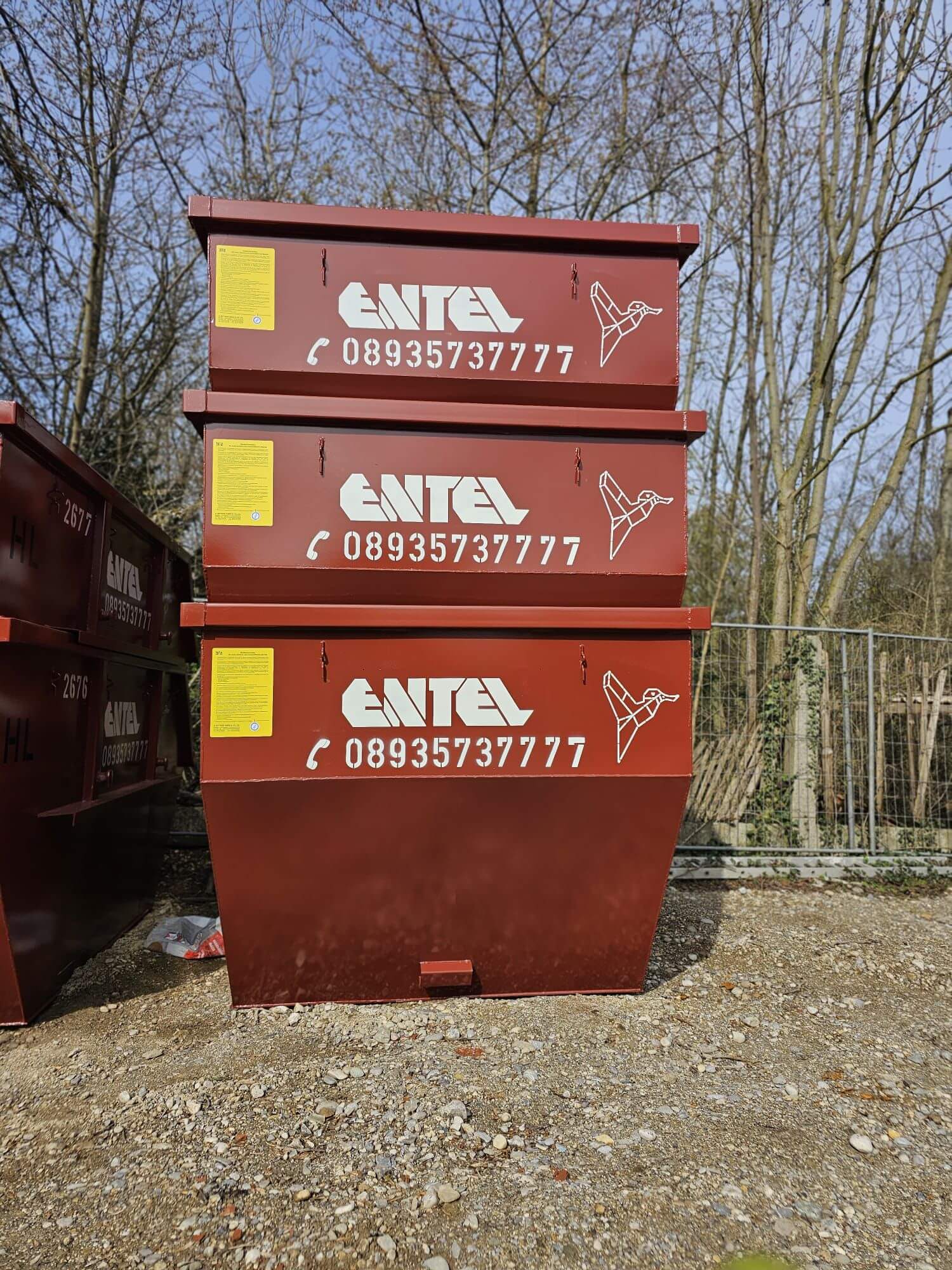 Drei rote Entel-Container vor Schrottplatz-Kulisse